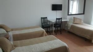 a room with two beds and a table and chairs at Pension Santa Rita in Santiago de Compostela