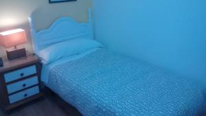 a blue bedroom with a bed and a night stand at Pension Santa Rita in Santiago de Compostela