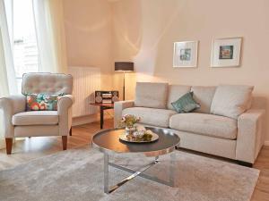 ein Wohnzimmer mit einem Sofa, einem Tisch und einem Stuhl in der Unterkunft Residenz "bel-vital" Binz - WG21 mit Balkon und seitlichem Meerblick in Binz