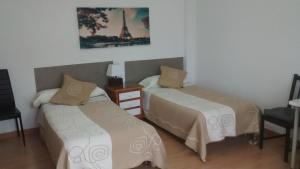a bedroom with two beds and a picture of the eiffel tower at Pension Santa Rita in Santiago de Compostela
