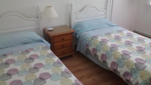 a bedroom with two beds and a night stand with a lamp at Pension Santa Rita in Santiago de Compostela