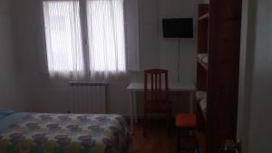 a bedroom with a bed and a desk and window at Pension Santa Rita in Santiago de Compostela