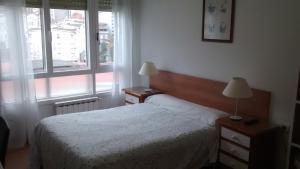 a bedroom with a bed and two lamps and a window at Pension Santa Rita in Santiago de Compostela