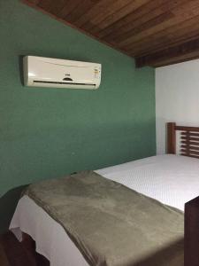 a bedroom with a bed with a air conditioner on a green wall at Pousada Recanto Verde e Mar in Araruama