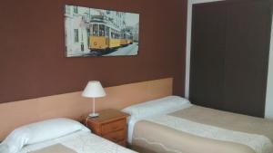 a bedroom with two beds and a picture of a train at Pension Santa Rita in Santiago de Compostela