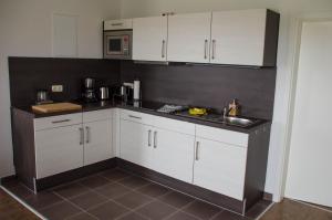 a kitchen with white cabinets and a sink at Ferienwohnung 2 Kormoran in Sagard +7 photos