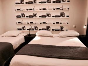マルセイユにあるオテル ボーセジュールのベッド2台 壁に写真が飾られた部屋