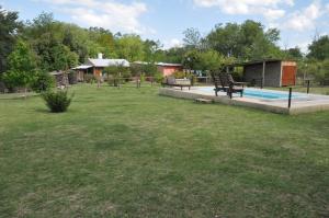 a yard with a swimming pool and a house at Cabañas Mi Refugio in Villa Giardino