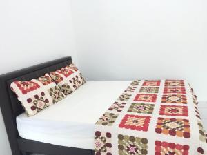 een bed met een quilt en een kussen erop bij Sleepee Homestay in Teluk Intan