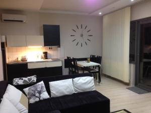 バラトンフレドにあるLUX Apartmanのリビングルーム(ソファ、壁掛け時計付)
