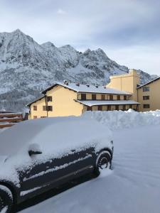 a car covered in snow with mountains in the background at Gran Baita in Passo del Tonale