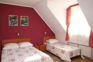 two beds in a bedroom with a red wall at Gościniec in Krynica Zdrój