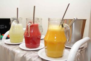 three glasses of juice on plates on a table at Fragata Apart Hotel in Marília
