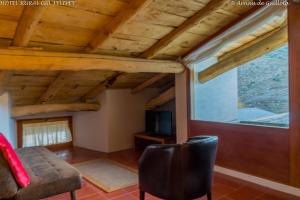 una sala de estar con techos de madera y una ventana en Cal Felipet Hotel Rural, en Olopte