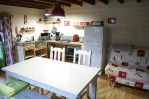 a kitchen with a white table and a refrigerator at Le gîte de Chomet in La Tour-dʼAuvergne