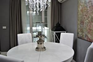 ローマにあるBig Tree Luxury Apartmentのダイニングルーム(白いテーブル、シャンデリア付)