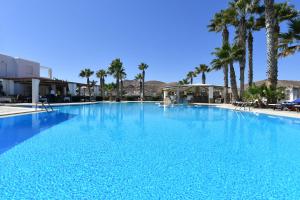 a large blue swimming pool with palm trees at Astir Of Paros in Naousa