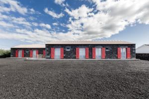 a house with red doors on a gravel lot at Ocean Breeze in Cais do Mourato