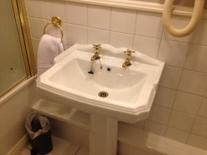 lavabo blanco en el baño con espejo en Ty Newydd Country Hotel, en Hirwaun