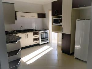 a kitchen with white cabinets and a white refrigerator at Edifício Summer Ville in Piratuba