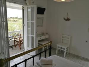 a room with a bed and a desk and a balcony at Kalimera Studios in Pollonia