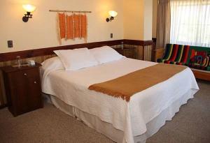 a hotel room with a large bed and a chair at Hotel Encanto del Río in Valdivia