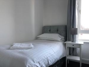 a white bedroom with a bed and a night stand at Wellesley Apartment in Leven