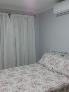 Un dormitorio con una cama con una manta de flores y una ventana en Ótimo Apto. em Bombas, en Bombinhas