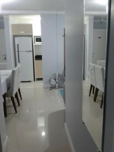 a white kitchen with a table and chairs and a room at Ótimo Apto. em Bombas in Bombinhas