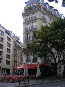 a building with tables and umbrellas in front of it at Paris Lady Mimi in Paris