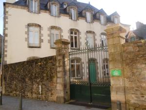 un ancien bâtiment avec une clôture et une porte verte dans l'établissement Quimper-Appart, à Quimper