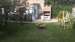 une cour avec une aire de jeux, une table et des chaises dans l'établissement Apart Los Ciruelos, à Huerta Grande