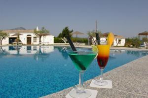 two cocktails sitting on a ledge next to a swimming pool at Santa Maria Resort in Orosei