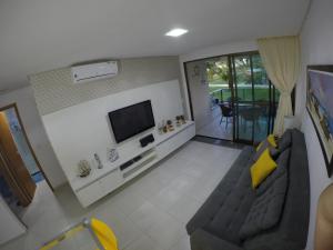 a living room with a couch and a flat screen tv at Carneiros Beach Resort in Praia dos Carneiros