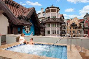 a woman and a child sitting in a swimming pool at The Arrabelle at Vail Square, a RockResort in Vail