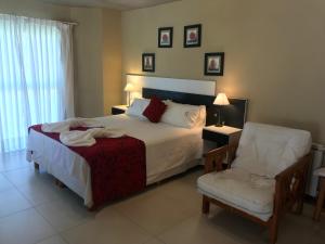 a bedroom with a large bed and a chair at Complejo Pampa in Mar de las Pampas