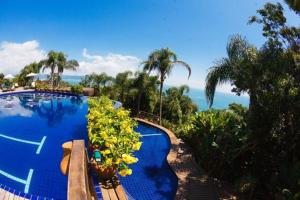 a resort swimming pool with a view of the ocean at Resort Refúgio do Estaleiro in Porto Belo