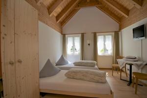 a bedroom with two beds and a table and windows at Gasthaus Skiklub in Andermatt