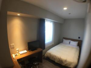 a bedroom with a bed and a desk with a television at Hotel Crown Hills Onahama in Iwaki