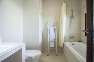 Un baño blanco con inodoro y bañera. en Soraya Apartment Seminyak, en Seminyak