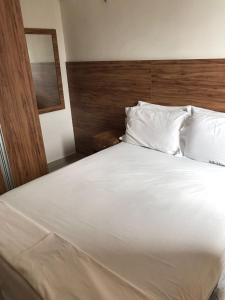 a white bed with a wooden headboard and white pillows at V G Fun Praia Do Futuro in Fortaleza +23 photos