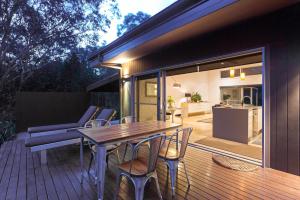 una terraza de madera con mesa y sillas de madera en Deja Vu Estate, en Pokolbin