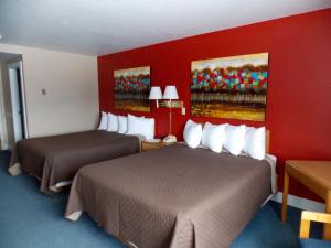 a hotel room with two beds and a red wall at The Washburn Inn in Washburn