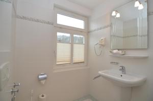 Baño blanco con lavabo y espejo en Villa Malepartus - Wohnung 07, en Binz