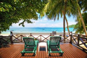 two chairs and a table on a deck with the beach at Tuna Bay Island Resort in Perhentian Islands