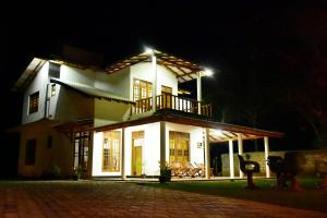 a white house with a balcony at night at Hotel Nimjaya in Udawalawe