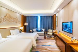 a hotel room with two beds and a flat screen tv at Jingling Shihu Garden Hotel  in Suzhou