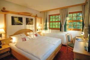 Schlafzimmer mit einem Bett, einem Schreibtisch und Fenstern in der Unterkunft Alpenhof in Gauting