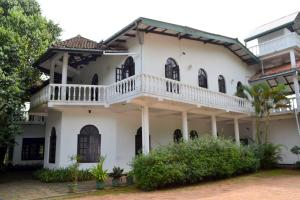 a large white house with a balcony at Hotel Breeta's Garden in Ginigathena