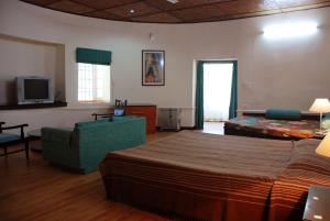 a bedroom with a bed and a couch and a tv at Alasia Hotel in Kasauli